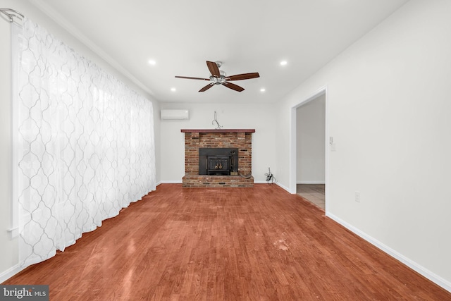 unfurnished living room featuring wood-type flooring, an AC wall unit, and ceiling fan