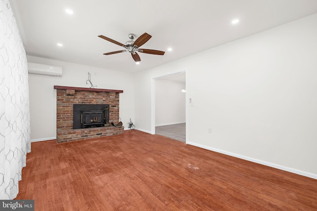 unfurnished living room with ceiling fan, wood-type flooring, and a wall unit AC