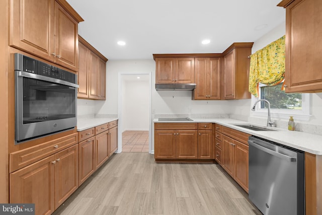 kitchen with appliances with stainless steel finishes, sink, and light hardwood / wood-style flooring