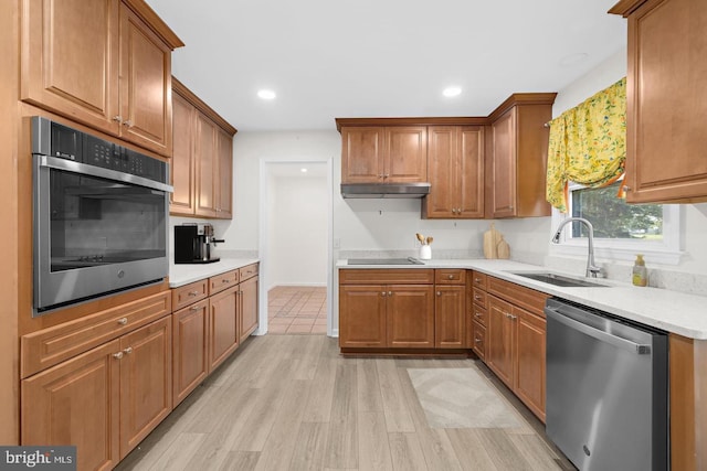 kitchen with appliances with stainless steel finishes, sink, and light hardwood / wood-style floors