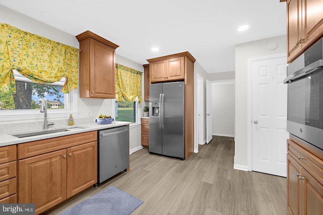 kitchen featuring light stone counters, stainless steel appliances, light hardwood / wood-style floors, and sink