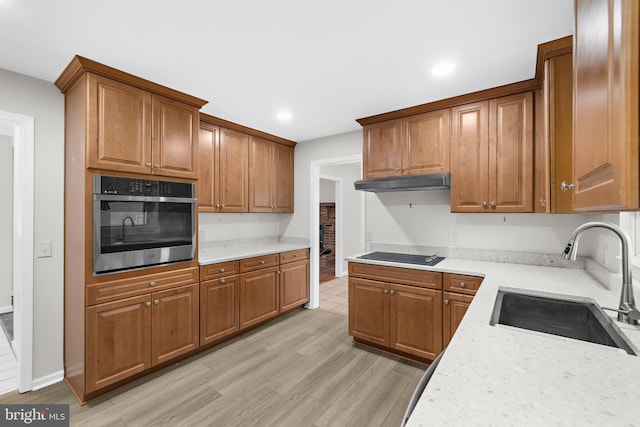 kitchen with sink, light hardwood / wood-style flooring, light stone countertops, black electric cooktop, and stainless steel oven