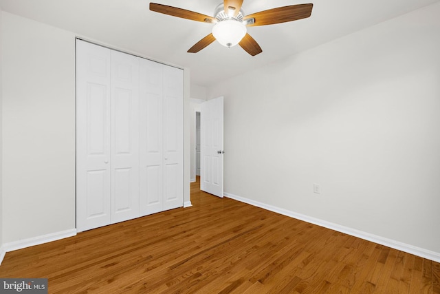 unfurnished bedroom with hardwood / wood-style flooring, ceiling fan, and a closet