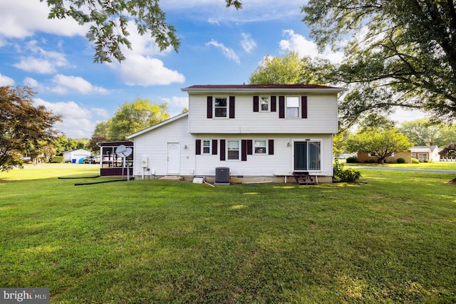 rear view of property featuring central AC unit and a lawn