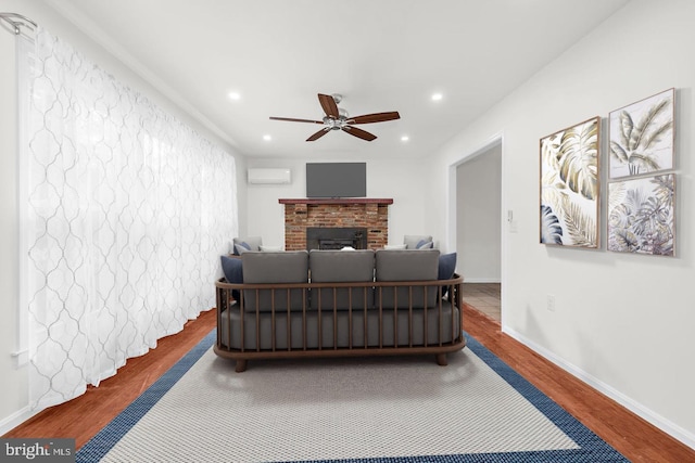 bedroom with a wall mounted air conditioner, hardwood / wood-style floors, a brick fireplace, and ceiling fan