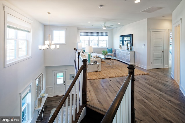 stairway with hardwood / wood-style floors and ceiling fan with notable chandelier