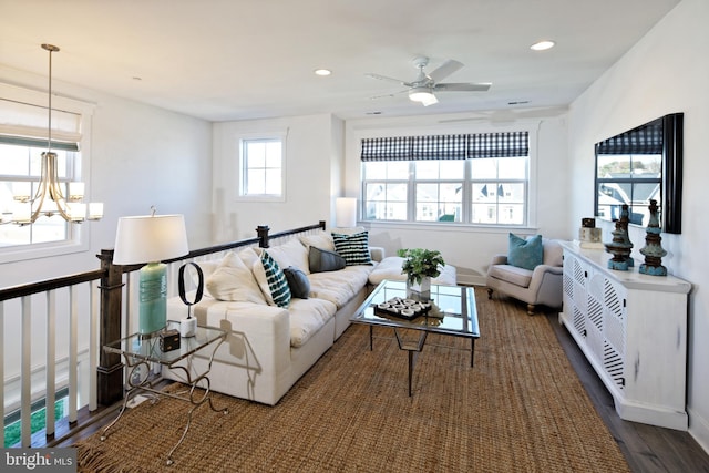 living room featuring ceiling fan with notable chandelier, a healthy amount of sunlight, and dark wood-type flooring