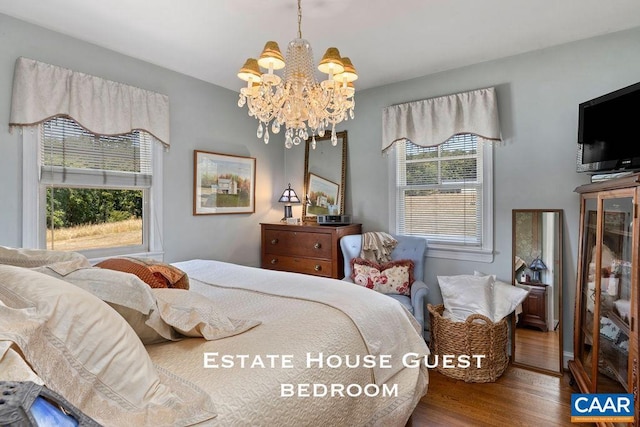 bedroom with hardwood / wood-style flooring and an inviting chandelier