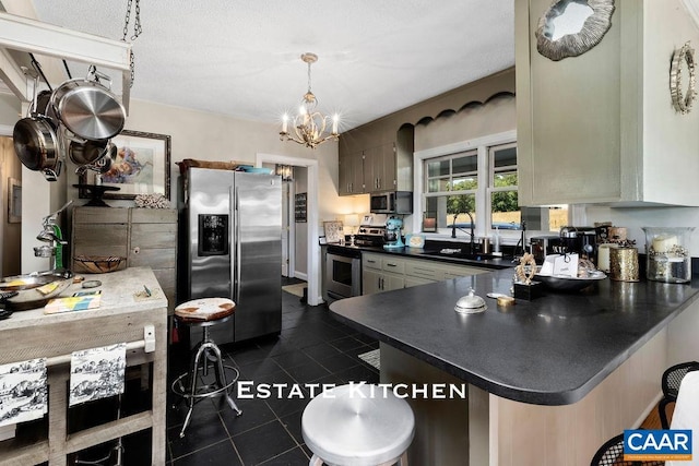 kitchen featuring an inviting chandelier, sink, dark tile patterned floors, kitchen peninsula, and stainless steel appliances