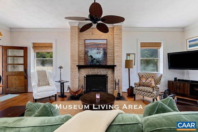 living room with a brick fireplace, ceiling fan, hardwood / wood-style floors, and ornamental molding