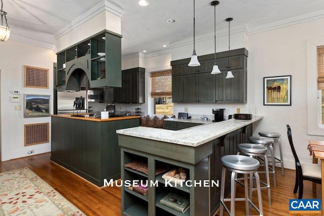 kitchen with kitchen peninsula, appliances with stainless steel finishes, decorative light fixtures, and dark hardwood / wood-style floors