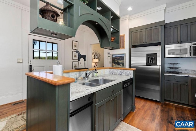 kitchen featuring dark wood-type flooring, crown molding, sink, appliances with stainless steel finishes, and light stone counters