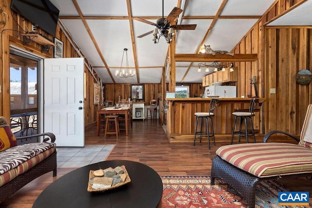 living room featuring wood walls, hardwood / wood-style floors, ceiling fan with notable chandelier, and lofted ceiling