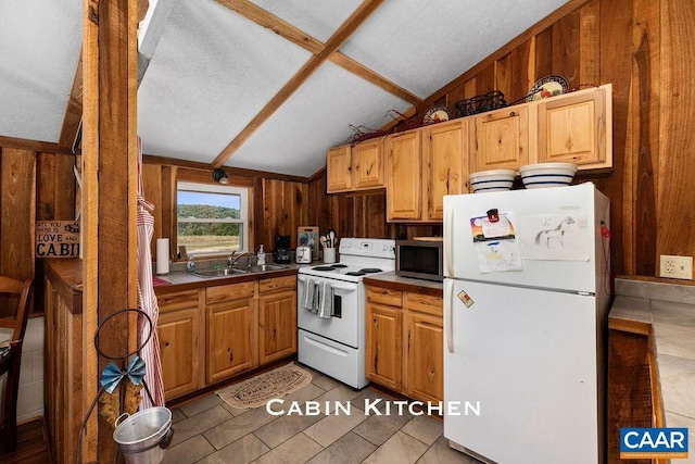 kitchen featuring white appliances, sink, light tile patterned floors, lofted ceiling, and wood walls