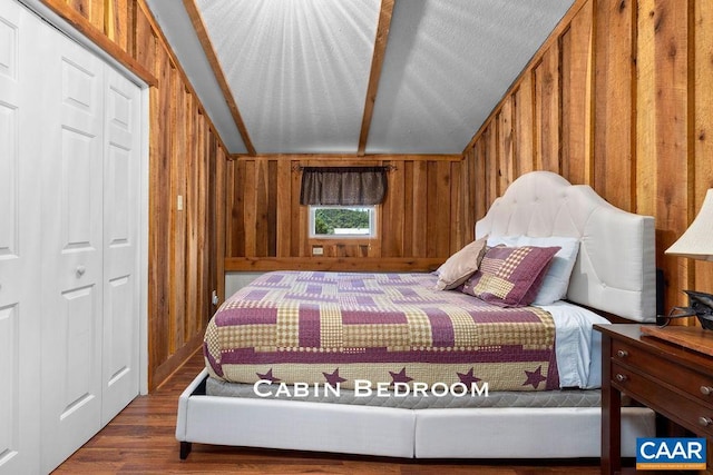 bedroom featuring a closet, wooden walls, hardwood / wood-style floors, and lofted ceiling with beams