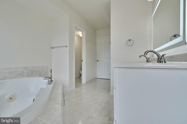 bathroom with tiled tub, vanity, toilet, and tile patterned floors