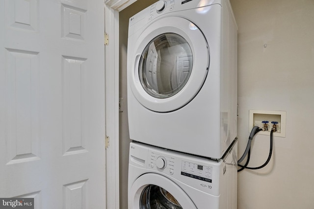 clothes washing area featuring stacked washing maching and dryer