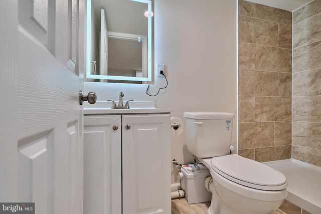 bathroom featuring tile patterned floors, vanity, a tile shower, and toilet