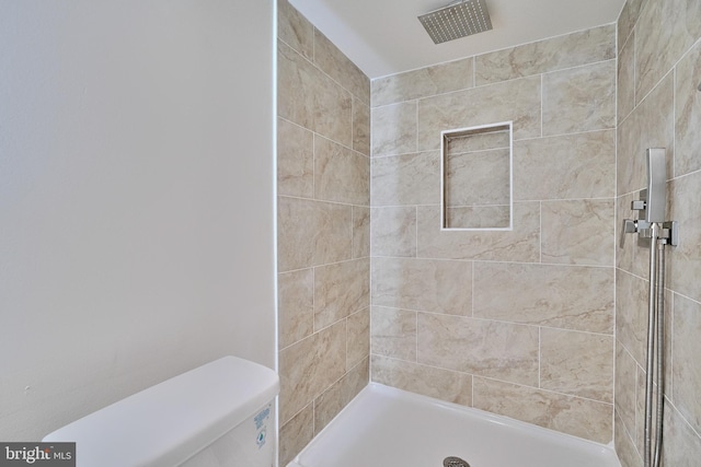 bathroom featuring tiled shower and toilet