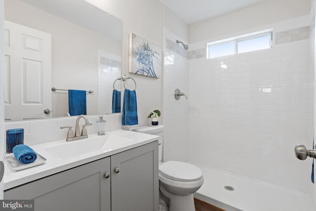 bathroom with vanity, toilet, and tiled shower