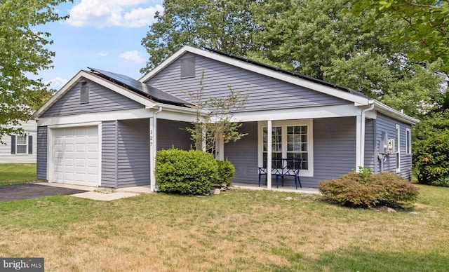 view of front facade with covered porch, solar panels, a garage, and a front lawn