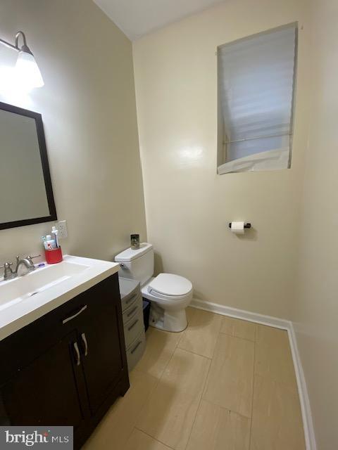 bathroom with toilet, baseboards, and vanity