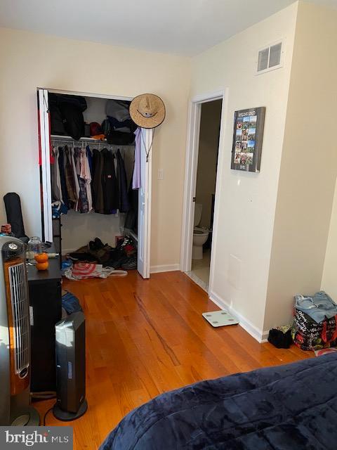 bedroom featuring baseboards, a closet, visible vents, and wood finished floors