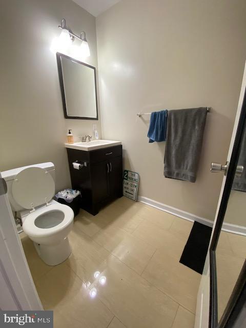 half bath with toilet, baseboards, and vanity