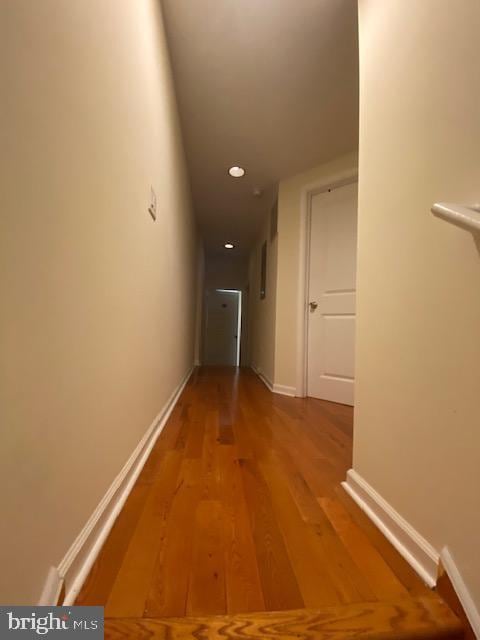 corridor with baseboards and wood finished floors