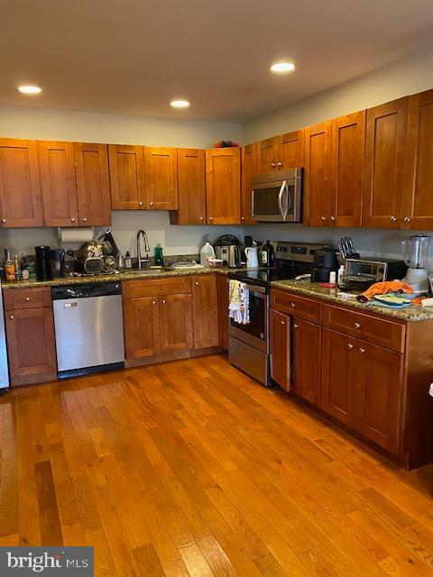 kitchen with hardwood / wood-style flooring, dark stone countertops, sink, and appliances with stainless steel finishes