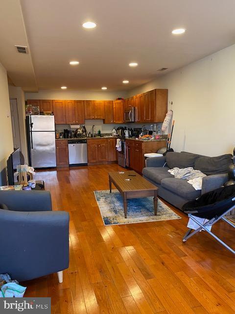 living area featuring visible vents, light wood-style flooring, and recessed lighting