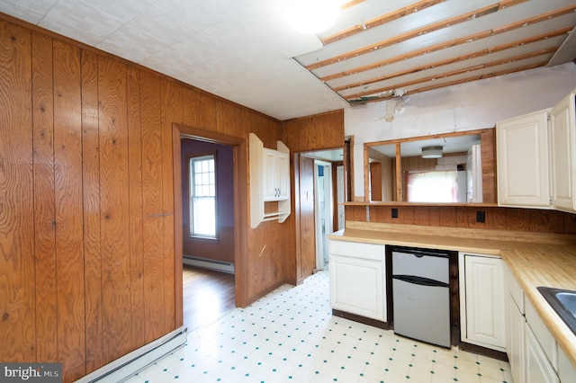 kitchen featuring fridge, white cabinets, wooden walls, and a baseboard radiator