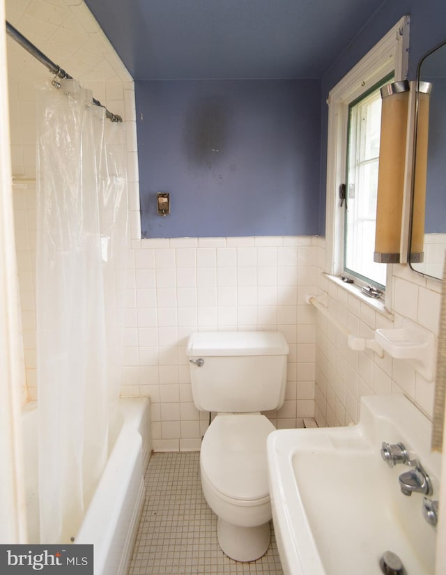 full bathroom featuring sink, shower / bath combo with shower curtain, tile patterned floors, tile walls, and toilet