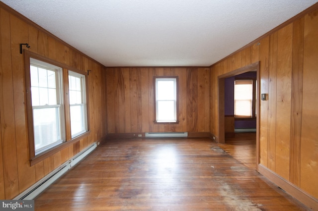 empty room with a baseboard radiator, dark hardwood / wood-style floors, wood walls, and a textured ceiling