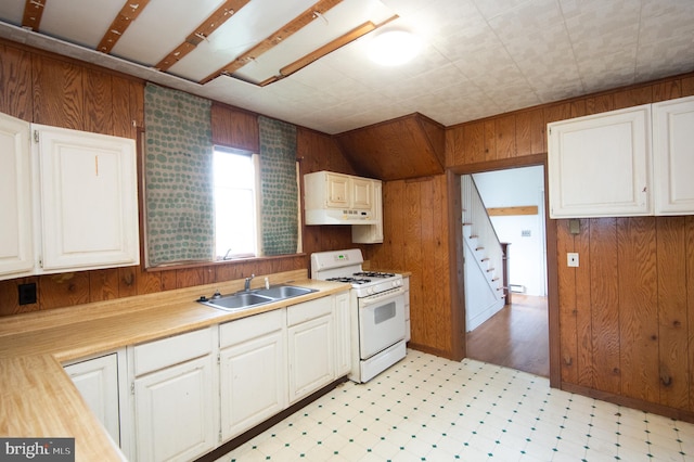 kitchen featuring white cabinetry, wood walls, and gas range gas stove