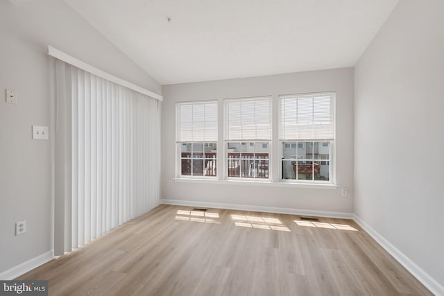 empty room featuring light hardwood / wood-style floors and vaulted ceiling