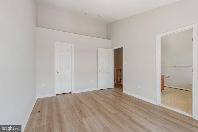 unfurnished bedroom featuring ensuite bathroom and light wood-type flooring