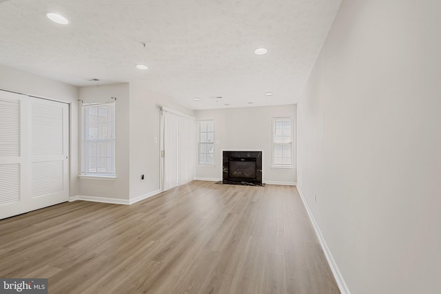 unfurnished living room featuring a fireplace, a textured ceiling, and light hardwood / wood-style flooring