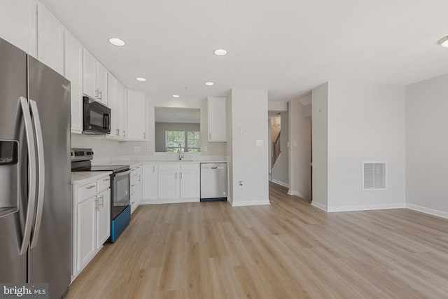 kitchen featuring stainless steel appliances, light hardwood / wood-style floors, white cabinets, and sink