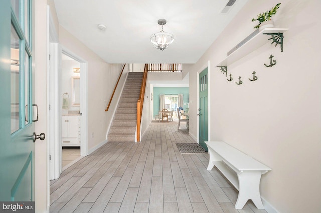 entryway with light hardwood / wood-style flooring and an inviting chandelier