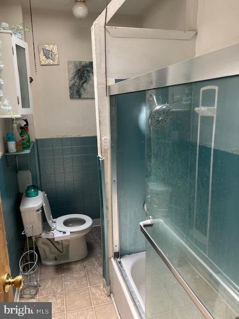 bathroom featuring tiled shower / bath, tile patterned flooring, and toilet