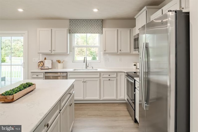 kitchen featuring stainless steel appliances, white cabinetry, sink, and light hardwood / wood-style flooring