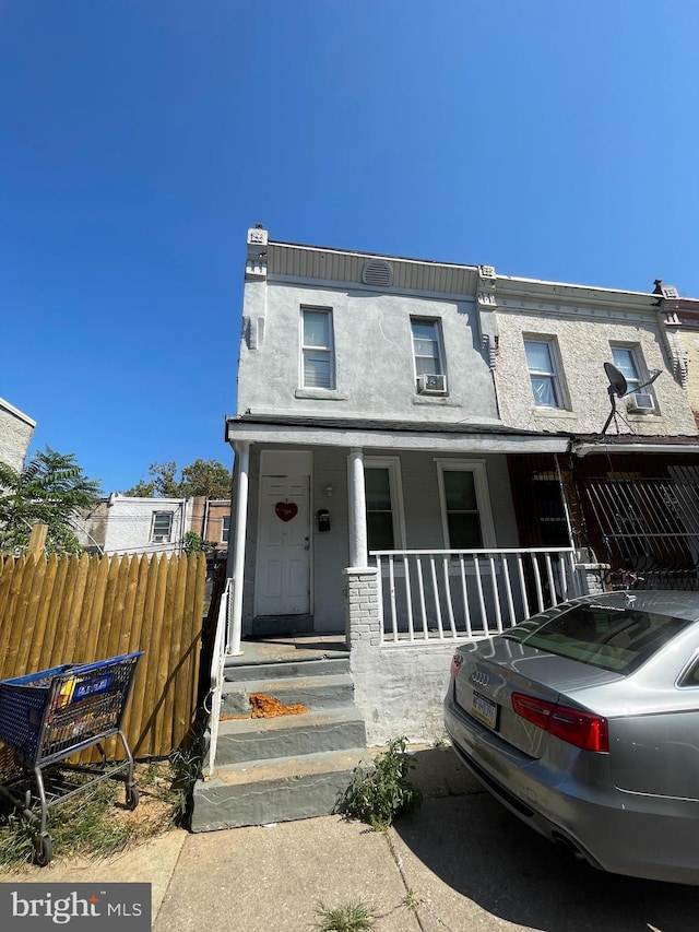 townhome / multi-family property featuring a porch, fence, and stucco siding