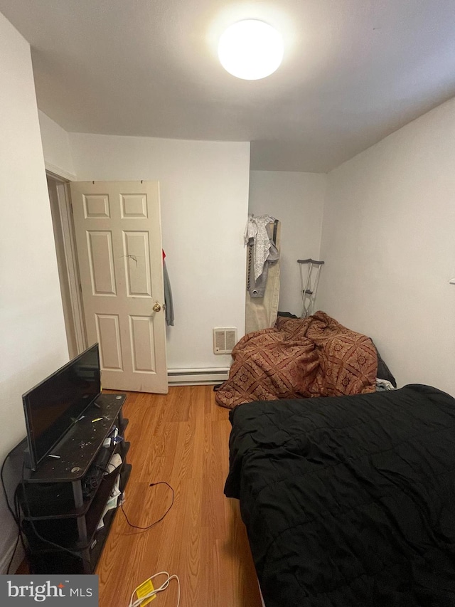 bedroom with a baseboard radiator and light hardwood / wood-style flooring