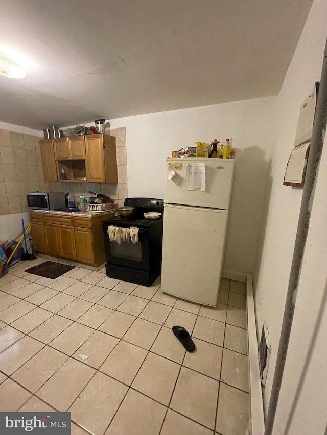 kitchen featuring black range with electric stovetop, white refrigerator, and light tile patterned flooring