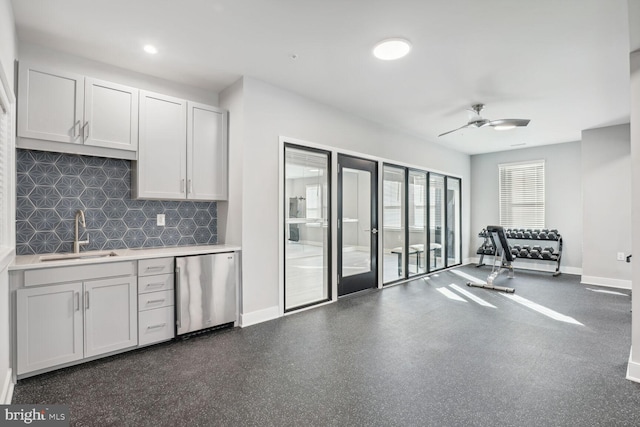 kitchen with ceiling fan, sink, stainless steel dishwasher, backsplash, and white cabinets