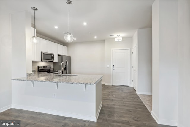 kitchen with sink, kitchen peninsula, appliances with stainless steel finishes, decorative light fixtures, and white cabinetry