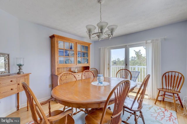 dining space featuring a notable chandelier, a textured ceiling, and light hardwood / wood-style floors