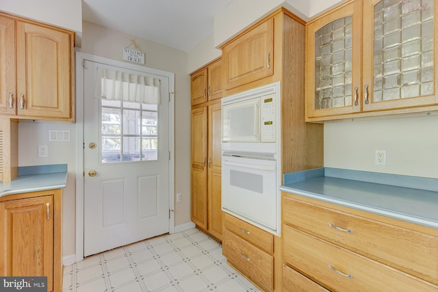 kitchen with light brown cabinetry and white appliances