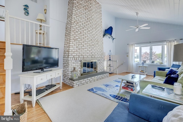 living room featuring hardwood / wood-style floors, a fireplace, high vaulted ceiling, and ceiling fan